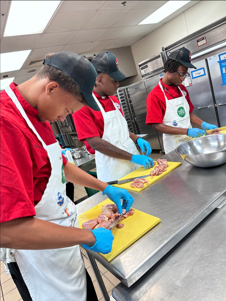 students cleaning chicken in kitchen